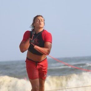 A man in red shorts and a black shirt is on the beach